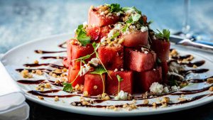 a white plate topped with watermelon slices covered in toppings.
