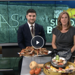 a man and a woman standing in front of a table full of food.