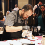 a man in an apron preparing food at a restaurant.