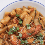 a white plate topped with pasta and meat.