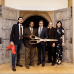 a group of people standing in front of a door holding a pair of scissors.