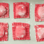 a white plate topped with four red cookies covered in icing.