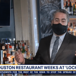 a man wearing a face mask in front of a bar.