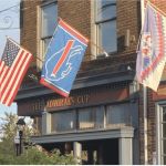 a row of flags hanging from the side of a building.