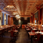 a restaurant with tables and chairs and a brick wall.