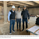 three men standing next to each other in a building.