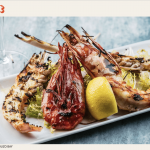a white plate topped with shrimp and a lemon.