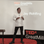a man standing on a stage giving a presentation.