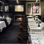a dining room with tables and chairs and a fire place.