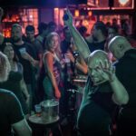 A group of people at a bar with their hands raised.