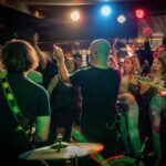 A group of people in a bar with a band on stage.