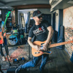 Two men playing guitars in a recording studio.