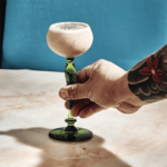 a person holding a wine glass on a table.