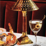 a table topped with a lamp next to a bowl of food.