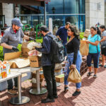 a group of people standing around a table with boxes of food.