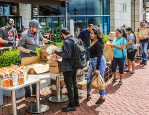 a group of people standing around a table with boxes of food.