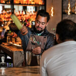 a man is making a drink at a bar.