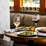 two plates of food and a glass of wine on a table.