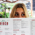 a woman holding up a menu for a restaurant.