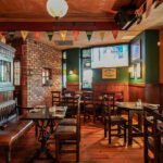 a restaurant with wooden tables and chairs and a brick wall.