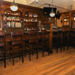 a bar with wooden chairs and a clock on the wall.