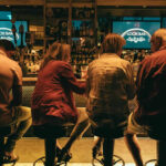 a group of people sitting at a bar.