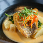 a black bowl filled with food on top of a wooden table.