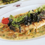 a white plate topped with a fish covered in sauce.
