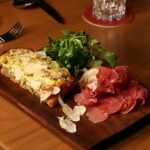 a wooden cutting board topped with meat and veggies.