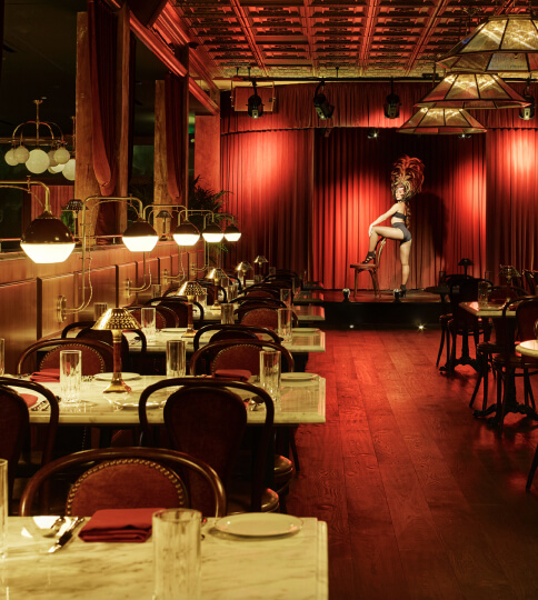 a room with tables and chairs and a red curtain.