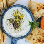a platter of hummus, pita chips, and hummus dips.