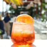 a glass filled with a drink sitting on top of a table.