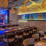 a restaurant with tables, chairs, and hanging lights.