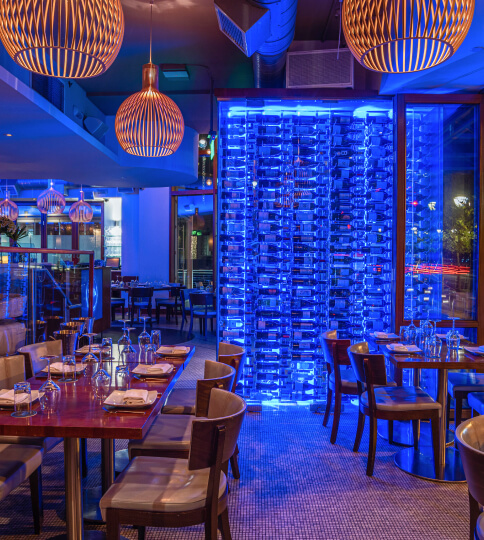 a restaurant with blue lighting and wooden tables.