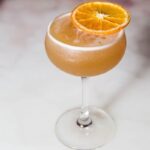 a drink with an orange slice on top of it.