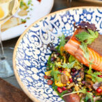 a plate of food on a table next to a glass of wine.