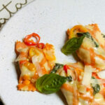 a white plate topped with ravioli and cheese.
