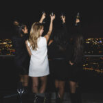 a group of women standing on top of a building.