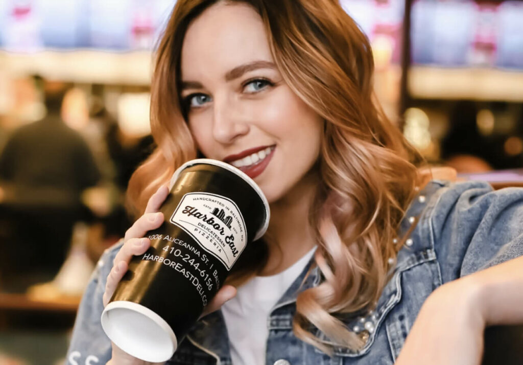 a woman holding a coffee cup and smiling.