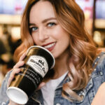 a woman holding a coffee cup and smiling.