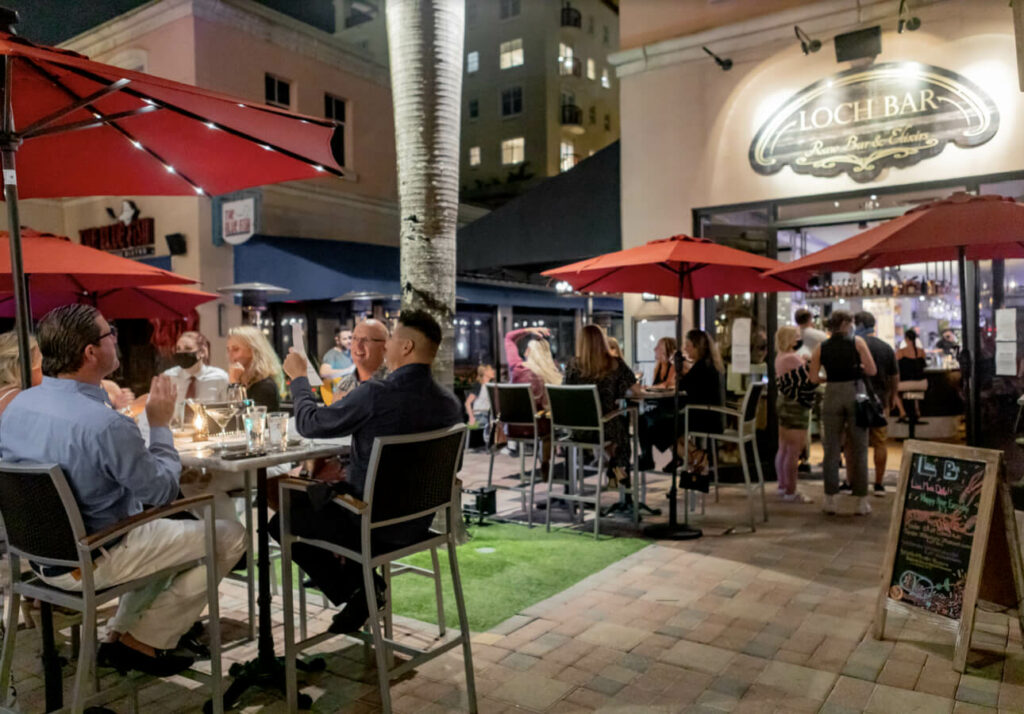 Evening diners enjoying the outdoor seating at Loch Bar Boca Raton