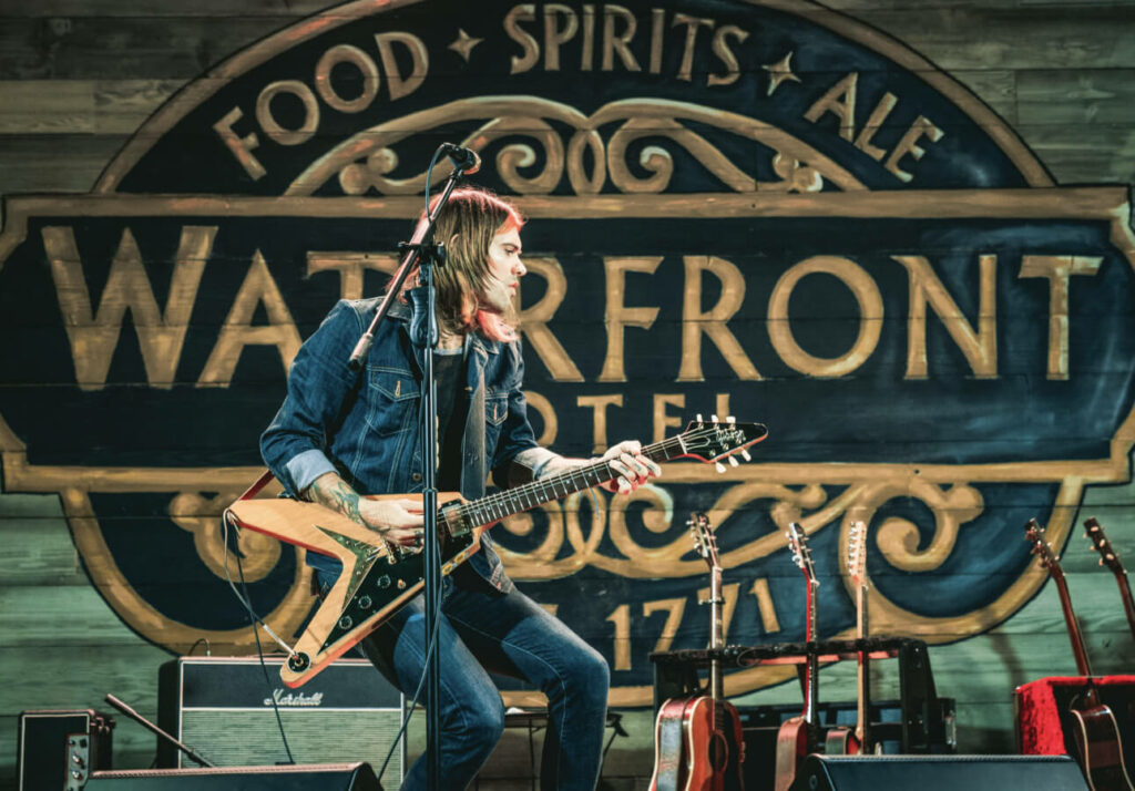 a man playing a guitar in front of a sign.