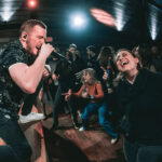 a man singing into a microphone in front of a group of people.