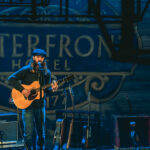 a man standing on a stage with a guitar.