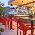 a restaurant with red chairs and a bar.