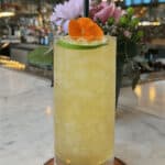 a tall glass filled with a drink on top of a table.