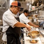 Two chefs preparing food in a restaurant kitchen.
