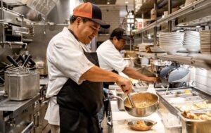 Two chefs preparing food in a restaurant kitchen.