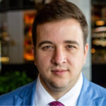 A man in a blue suit is standing in front of a bar.