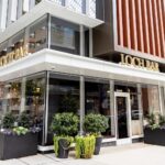 The exterior of a restaurant with a wooden table and chairs.